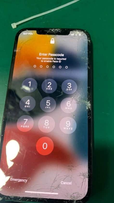 Cracked iPhone lock screen showing reduced brightness and poor visibility due to damage