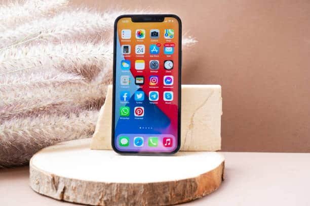 iPhone 12 with colorful home screen icons shown on a display stand