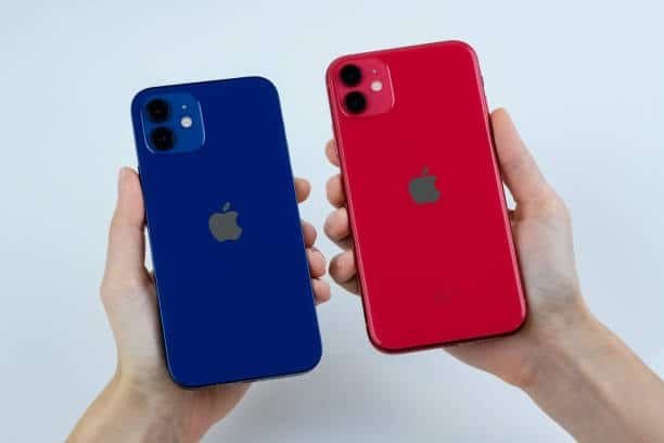 Back view of red and blue iPhone 12 units held side by side
