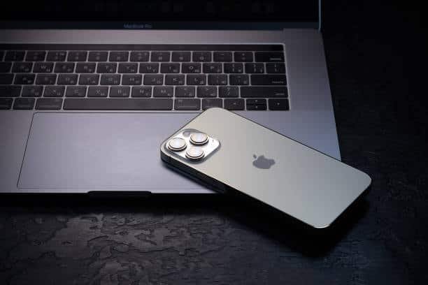 iPhone 15 Pro resting on a MacBook keyboard in a dark setting