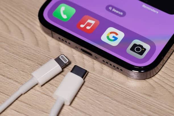 Close-up of iPhone 15 Pro with USB-C and Lightning cables for comparison