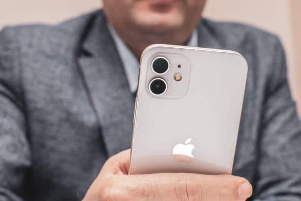 Close-up of a person holding a white iPhone 12 in hand