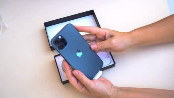 Hands unboxing a blue iPhone 12 from its retail packaging