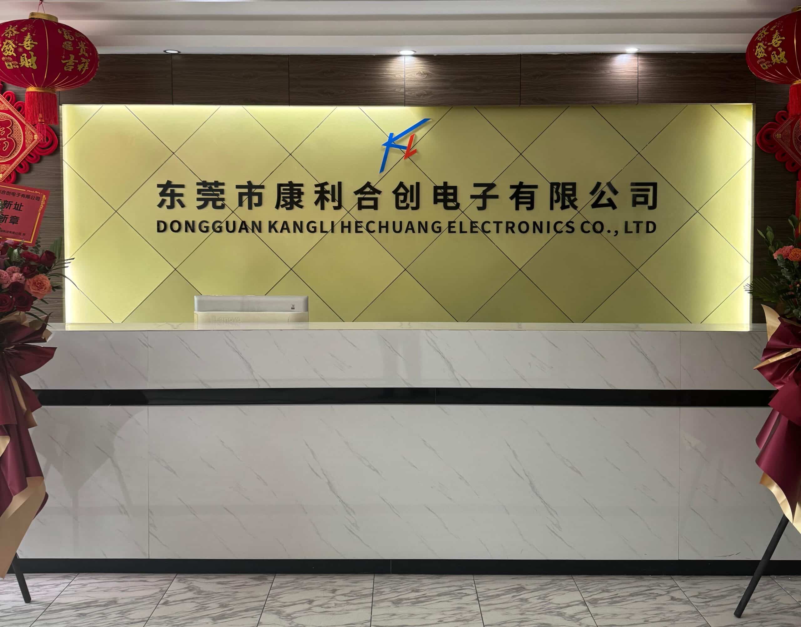 Reception of Dongguan Kangli Hechuang Electronics Co., Ltd: marble desk, illuminated company name/logo wall, red festive decor (lanterns, flowers) on sides.